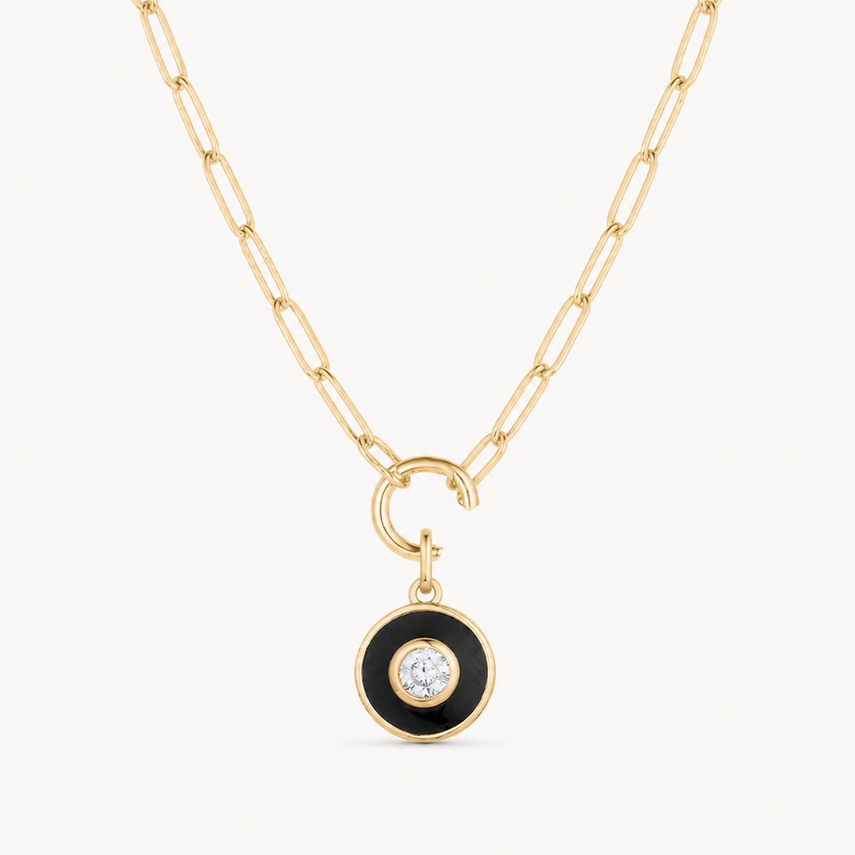 black enemel & cubic zirconia round charm shown on a gold paperclip charm necklace