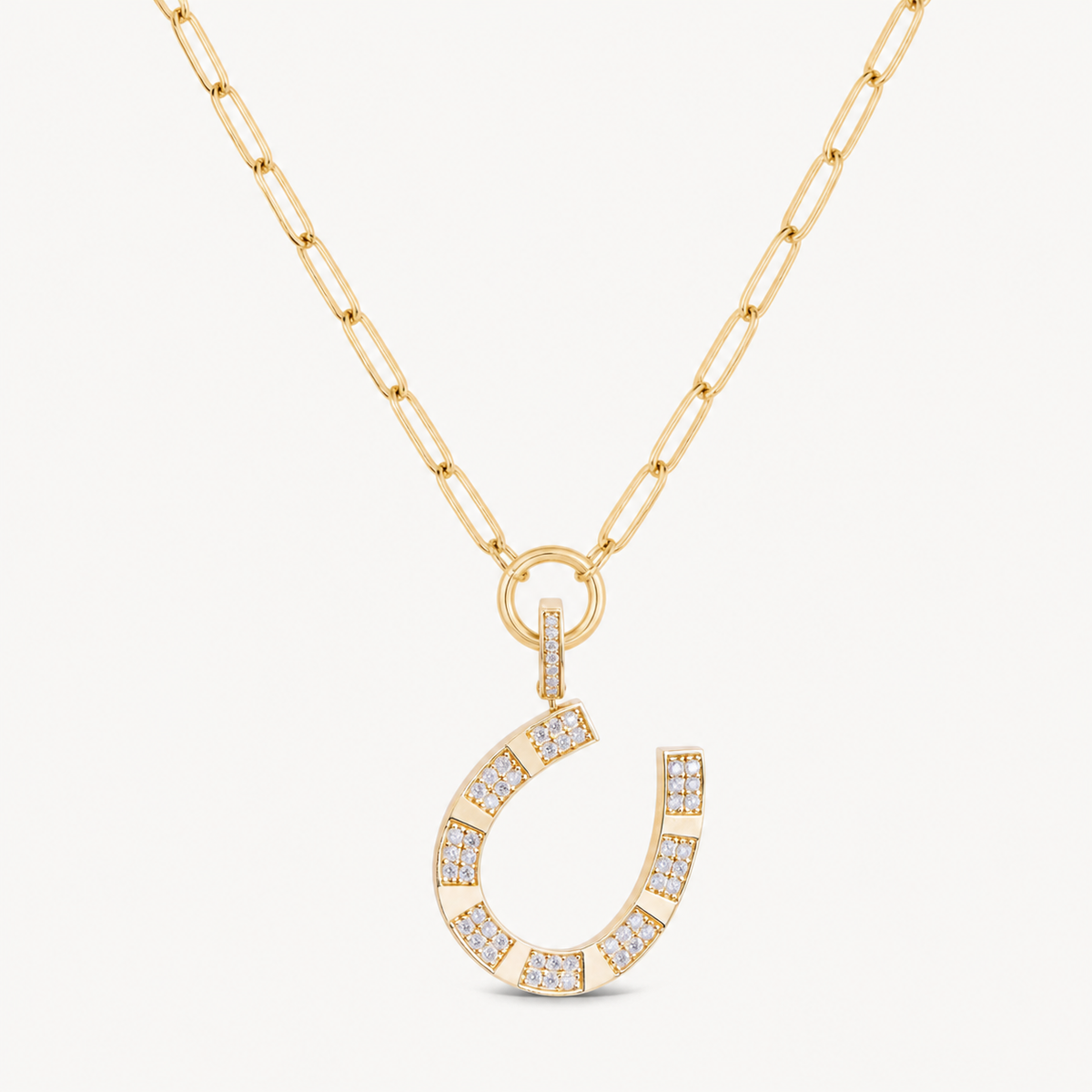 large gold and diamond horseshoe charm shown on a gold paperclip charm necklace