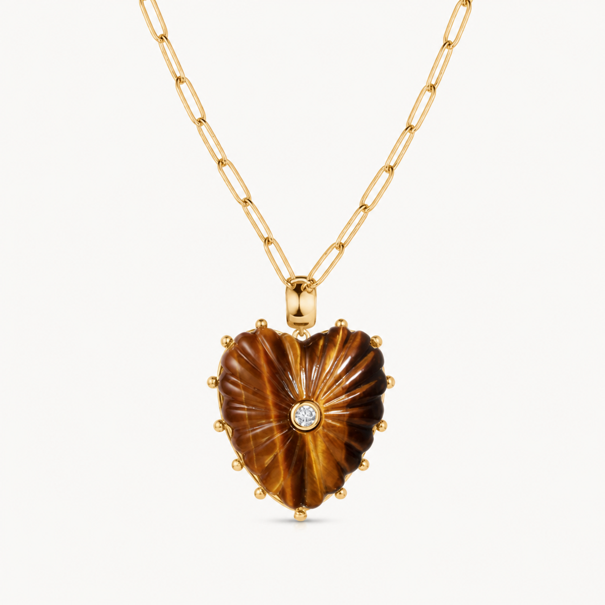 large tigerseye carved heart charm shown on a gold paperclip charm necklace