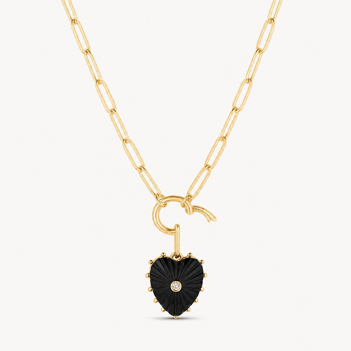 small black onyx carved heart charm shown on a gold paperclip charm necklace