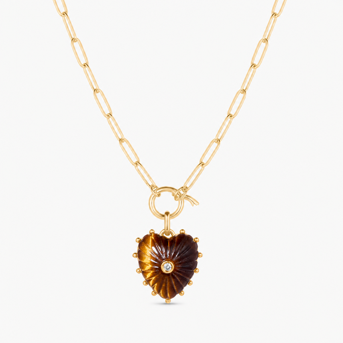 small tiger eye carved heart charm shown on a gold paperclip charm necklace