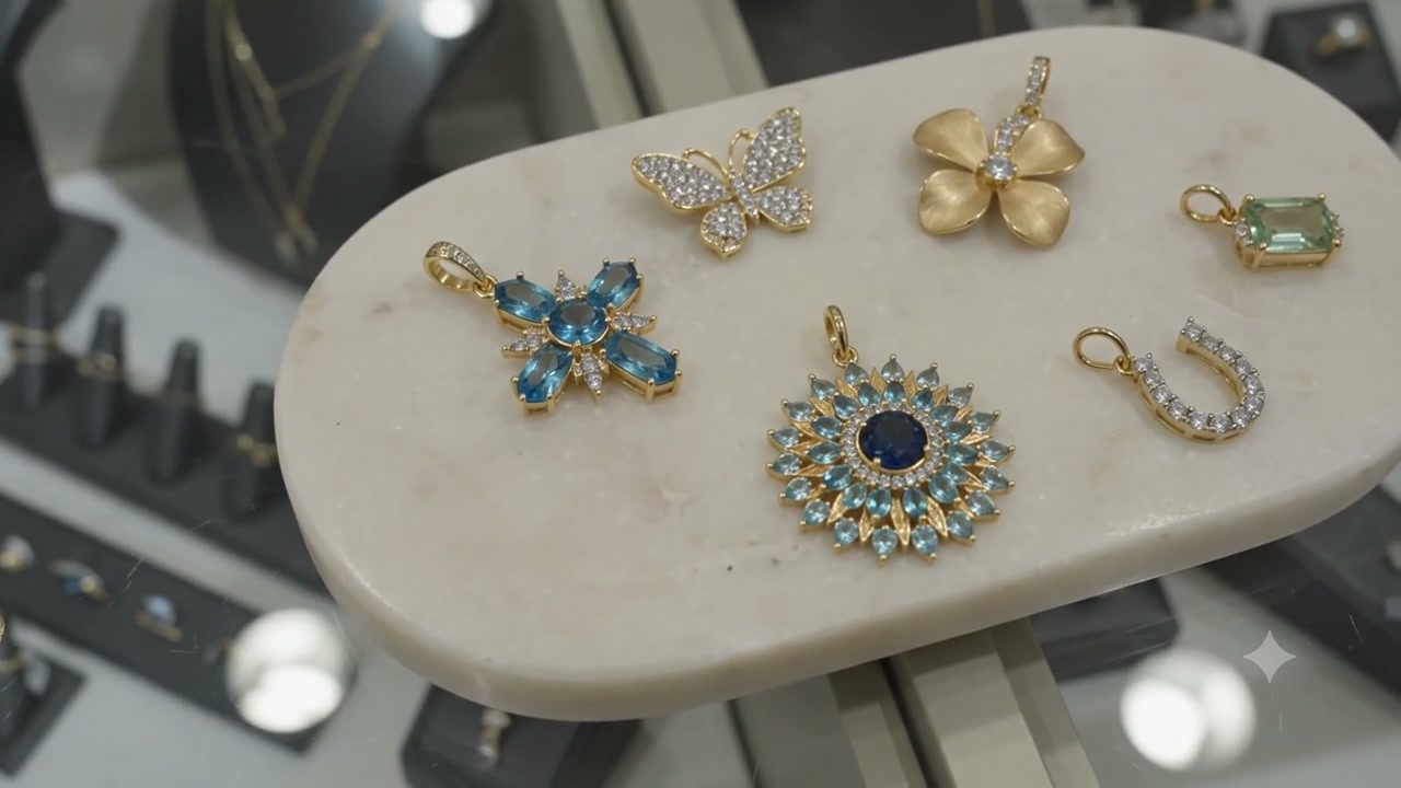 Gold, diamond, and gemstone charms arranged on a stone tray
